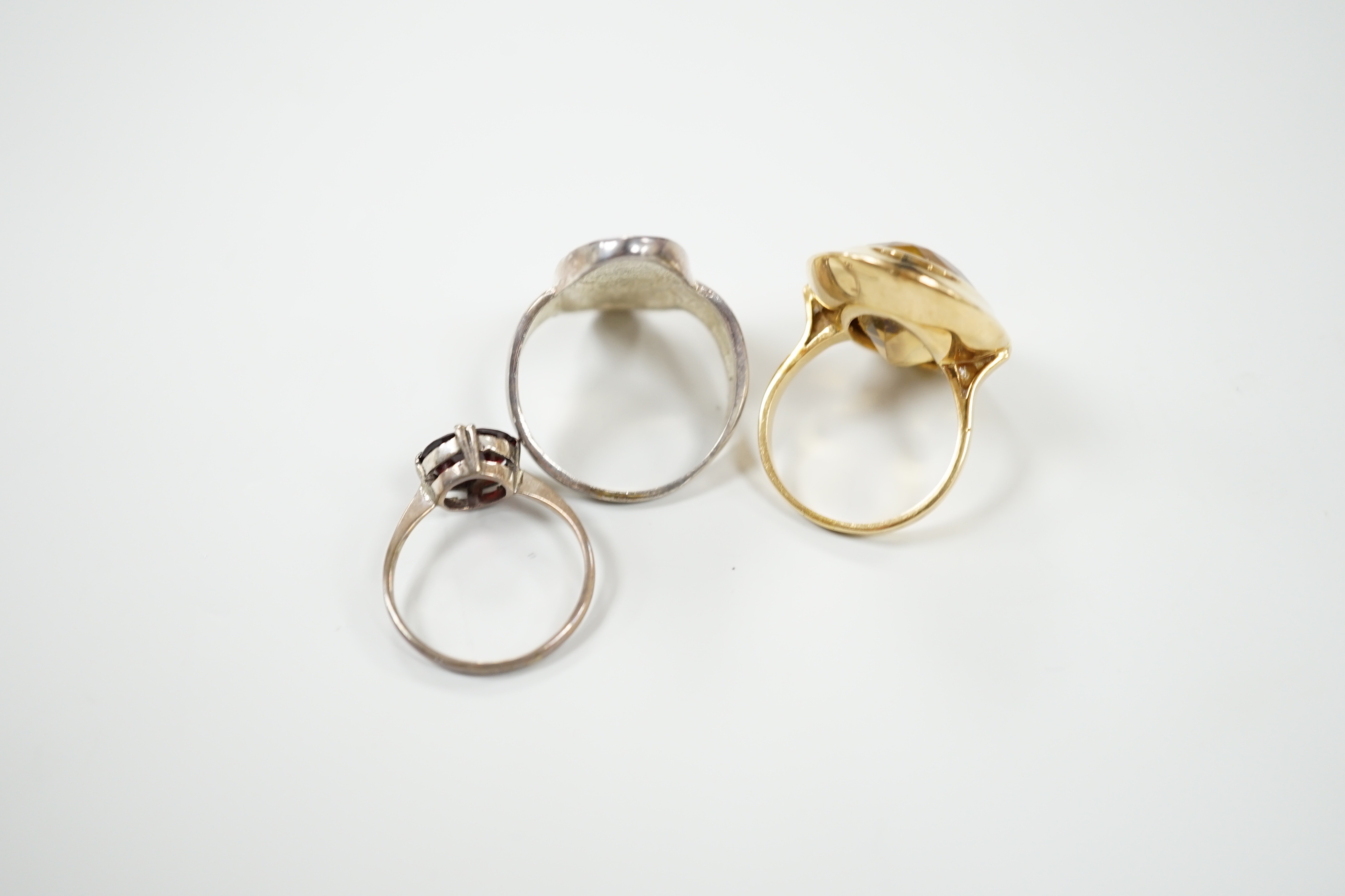 A yellow metal and oval cut citrine set dress ring, size M, gross 15.8 grams and two other rings.
